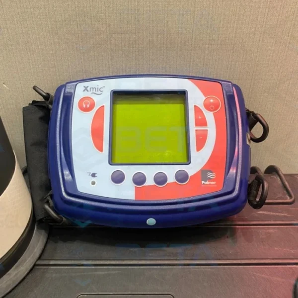 Close-up of the Palmer Xmic electronic acoustic water leak detector control unit showing its display screen, operation buttons, and branding
