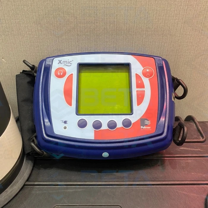 Close-up of the Palmer Xmic electronic acoustic water leak detector control unit showing its display screen, operation buttons, and branding