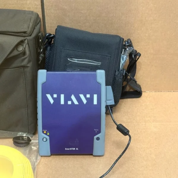 Front view of the Viavi JDSU ESL18FA65PPM SmartOTDR SL screenless filtered OTDR unit with carrying bags and accessories in the background.